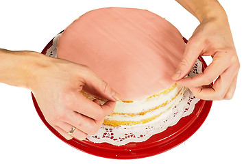 Image showing Professional cake baker making the final touch when covering a c