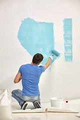 Image showing man with roller painting wall in blue at home