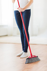 Image showing close up of woman legs with broom sweeping floor