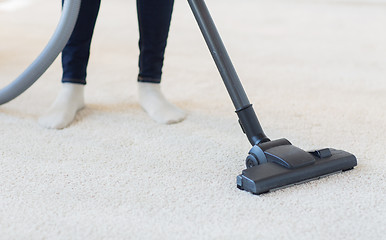 Image showing close up of woman legs with vacuum cleaner at home