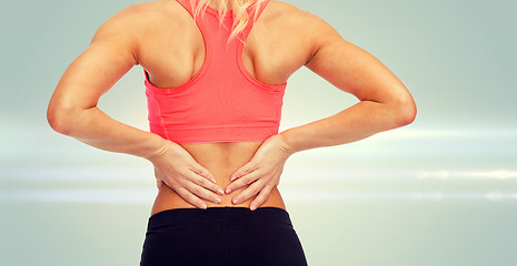 Image showing close up of sporty woman touching her back