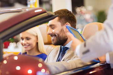 Image showing happy couple with car dealer in auto show or salon