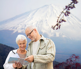 Image showing happy senior couple with travel map over mountains