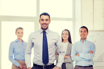 Image showing smiling businessman in office with team on back