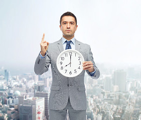 Image showing businessman in suit holding clock with 8 o\'clock