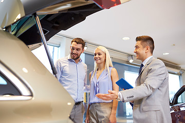 Image showing happy couple with car dealer in auto show or salon