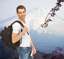 Image showing happy young man with backpack and book travelling