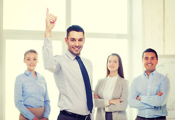 Image showing smiling businessman in office with team on back