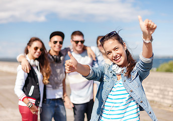 Image showing teenage girl with headphones and friends outside