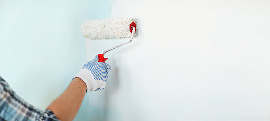 Image showing close up of male in gloves painting wall