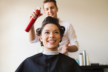 Image showing happy woman with stylist making hairdo at salon