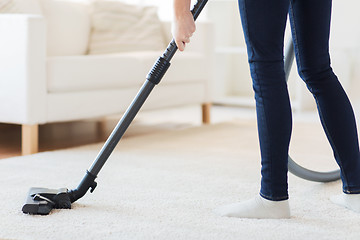 Image showing close up of woman legs with vacuum cleaner at home