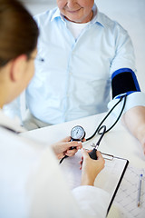 Image showing close up of doctor measuring blood pressure