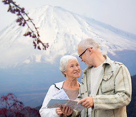 Image showing happy senior couple with travel map over mountains