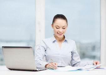 Image showing businesswoman with laptop and charts in office