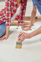 Image showing close up of couple smearing wallpaper with glue