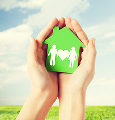 Image showing hands holding green house with family