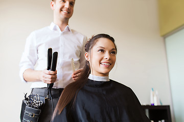 Image showing happy woman with stylist making hairdo at salon