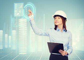 Image showing smiling businesswoman in helmet with clipboard