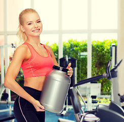 Image showing smiling sporty woman with jar of protein