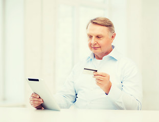 Image showing old man with tablet pc and credit card at home