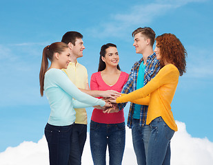 Image showing smiling teenagers with hands on top of each other