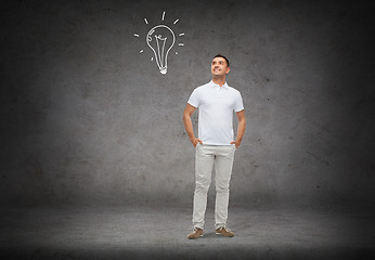 Image showing smiling man looking up to lighting bulb doodle