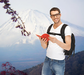 Image showing happy young man with backpack and book travelling