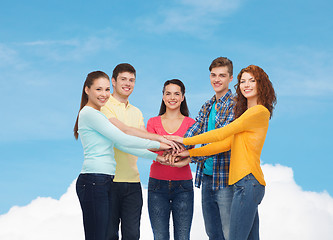 Image showing smiling teenagers with hands on top of each other