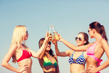 Image showing group of smiling young women drinking on beach