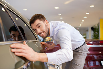 Image showing happy man touching car in auto show or salon