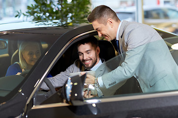 Image showing happy couple with car dealer in auto show or salon