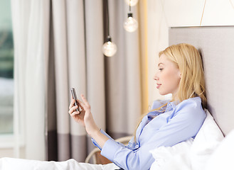 Image showing happy businesswoman with smartphone in hotel room