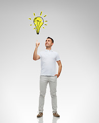 Image showing smiling man pointing finger to lighting bulb