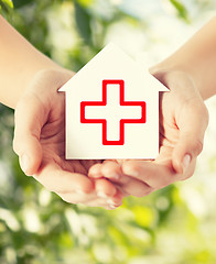 Image showing hands holding paper house with red cross