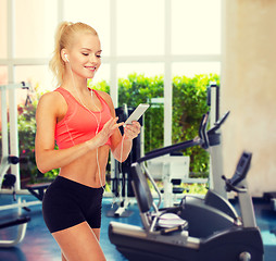 Image showing smiling sporty woman with smartphone and earphones