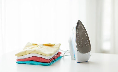 Image showing close up of iron and clothes on table at home