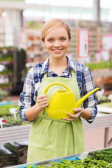 Image showing happy woman with watering can in greenhouse