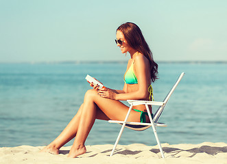 Image showing smiling young woman sunbathing in lounge on beach