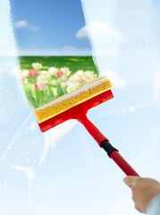 Image showing close up of hand cleaning window with sponge