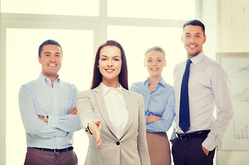 Image showing smiling businesswoman in office with team on back