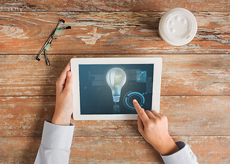 Image showing close up of hands with tablet pc and lighting bulb