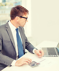 Image showing businessman with computer, papers and calculator