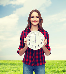 Image showing young woman in casual clothes with wall clock