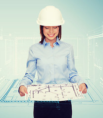 Image showing businesswoman in helmet looking at blueprint