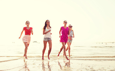 Image showing group of smiling women running on beach