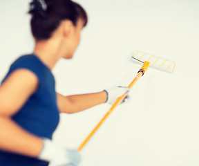 Image showing woman with roller and paint colouring the wall