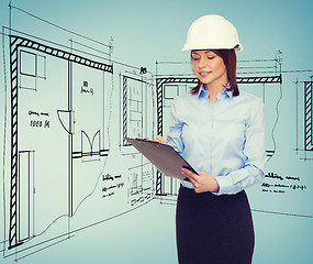 Image showing smiling businesswoman in helmet with clipboard