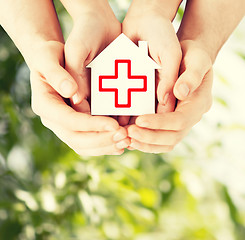 Image showing hands holding paper house with red cross