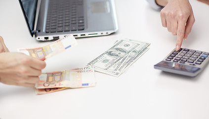 Image showing close up of hands counting money with calculator